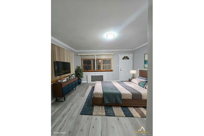 Bedroom with ornamental molding and wood finished floors