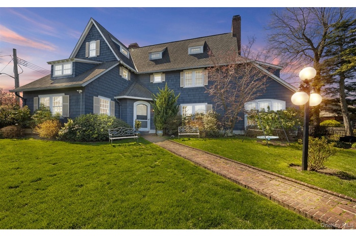 Traditional-style home with a chimney, a front yard, and a shingled roof