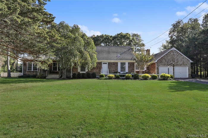 View of front of property with a shingled roof, asphalt driveway, and a garage