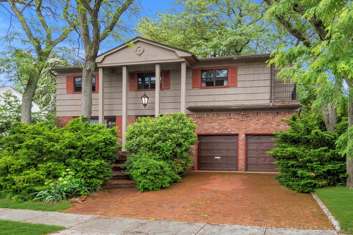 View of front of property featuring decorative driveway, a garage, and brick siding