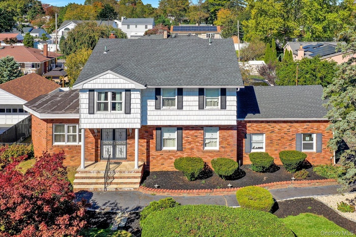 View of front facade with roof with shingles and brick siding
