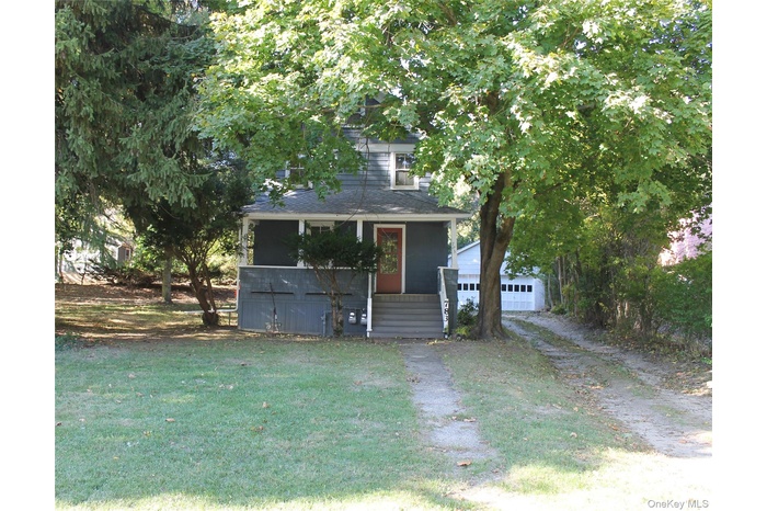View of front of property with a porch, a front yard, an outdoor structure, and a garage