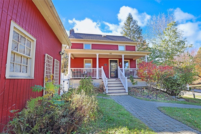View of front facade featuring covered porch and stairs