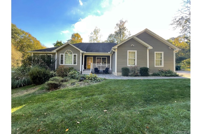 Ranch-style house featuring covered porch and a front lawn