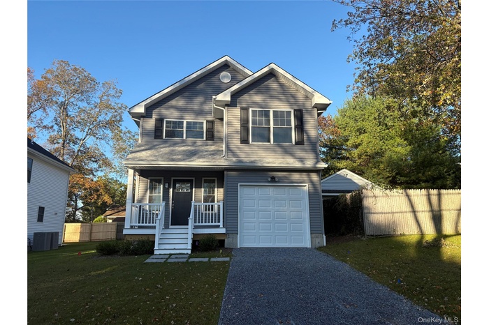 View of front facade featuring covered porch, a garage, and gravel driveway