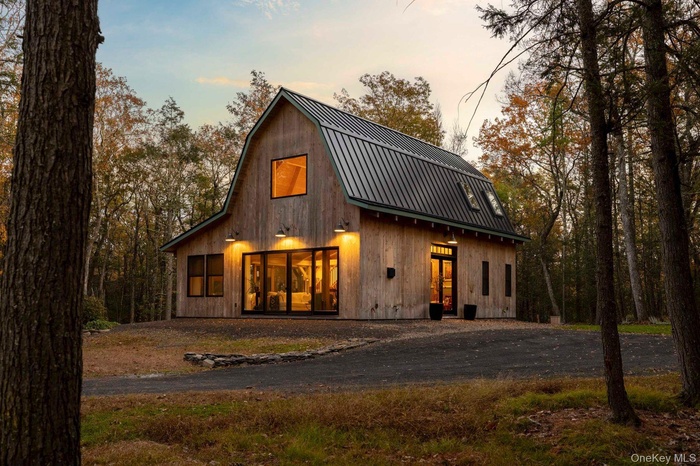 Front of house at dusk featuring a gambrel roof and a metal roof