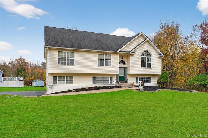 Split foyer home featuring a front lawn and roof with shingles