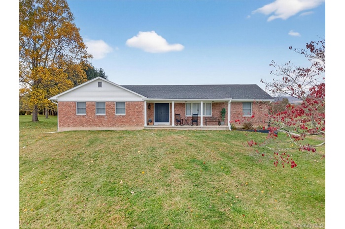 Ranch-style house with covered porch, a front lawn, brick siding, and a shingled roof