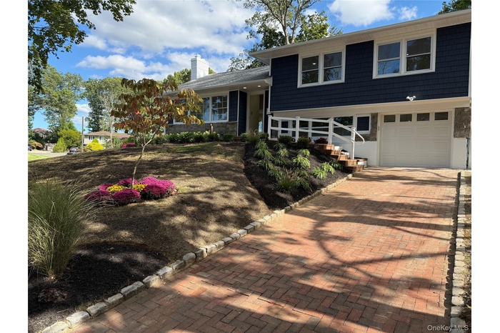 Tri-level home with a chimney, decorative driveway, and a garage