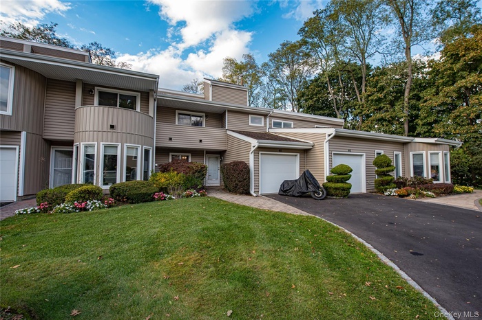 Town home with a garage, asphalt driveway, a front yard, and a balcony