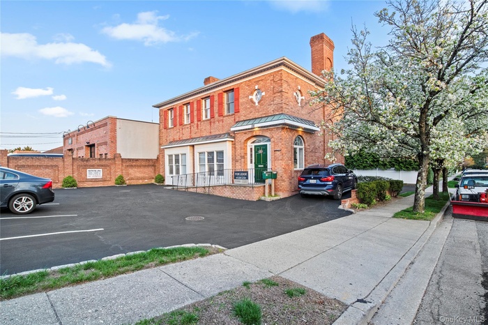 View of building exterior with uncovered parking and fence