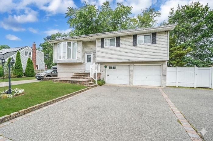 Split foyer home with driveway, an attached garage, and brick siding