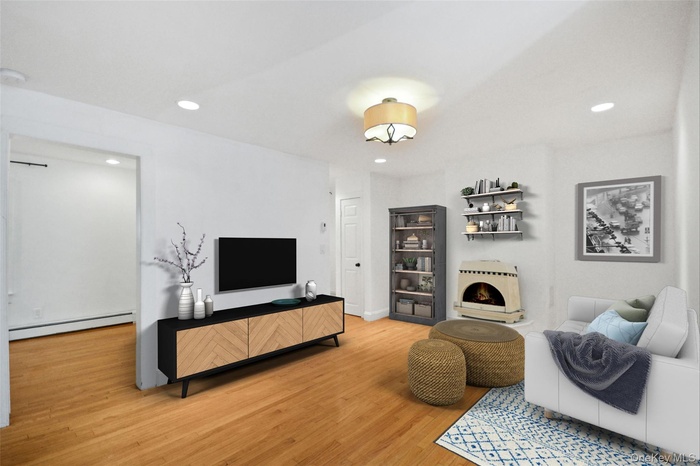 Living area featuring light wood-style floors, baseboard heating, and recessed lighting