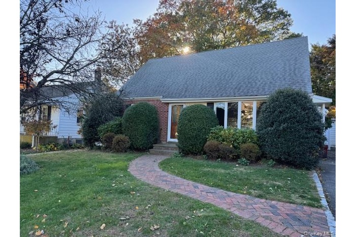 View of front of house with a front yard and a shingled roof