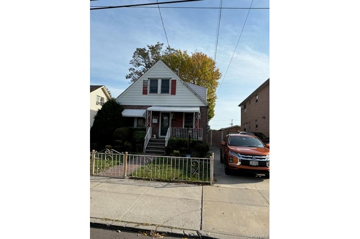 Bungalow-style house with a fenced front yard, a porch, brick siding, and a gate