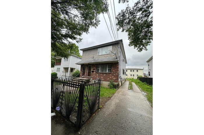View of front facade featuring brick siding, a fenced front yard, and a gate