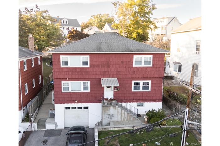 View of front of house featuring roof with shingles and stairway