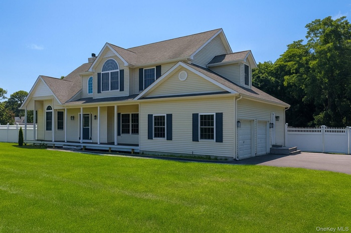 View of front of home with covered porch, asphalt driveway, a shingled roof, and a garage