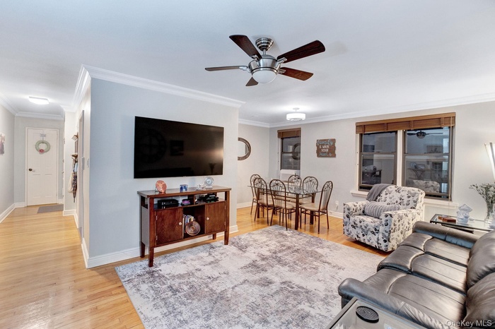 Living room featuring light wood finished floors, crown molding, and a ceiling fan