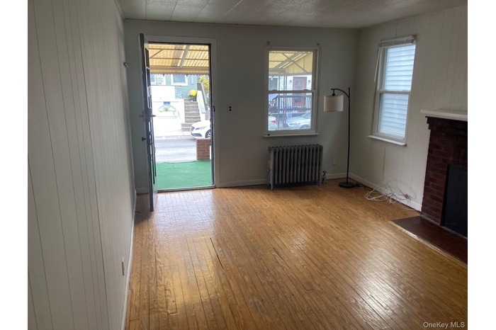 Unfurnished living room with wood walls, radiator, light wood-type flooring, and a fireplace