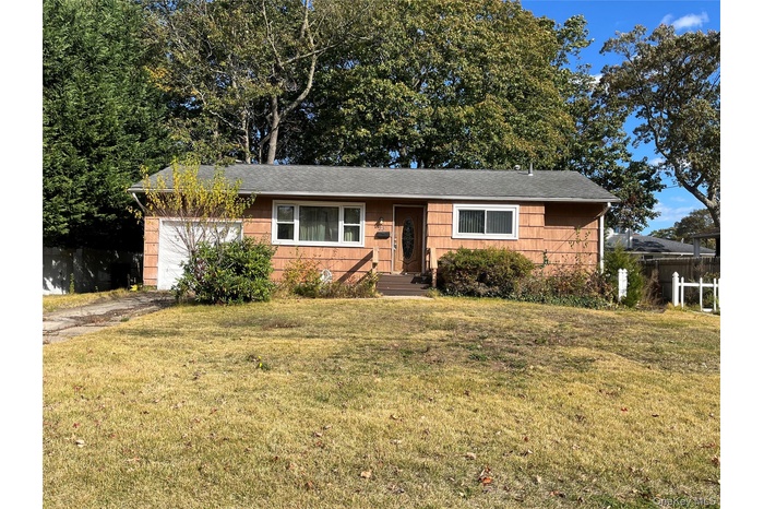Single story home featuring a front yard, a garage, and a shingled roof