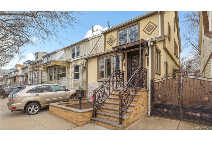 View of front of house with stucco siding, a gate, and stone siding