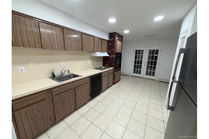 Kitchen featuring black appliances, light countertops, french doors, recessed lighting, and light tile patterned floors