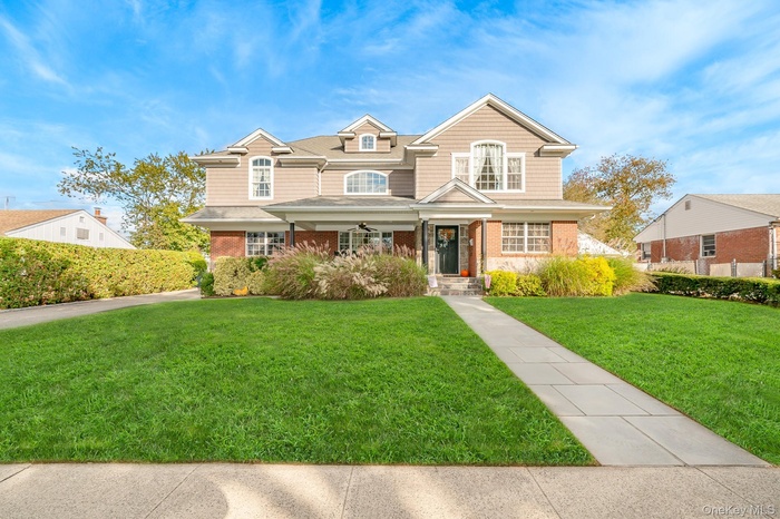 View of front facade with a front lawn, a porch, and brick siding