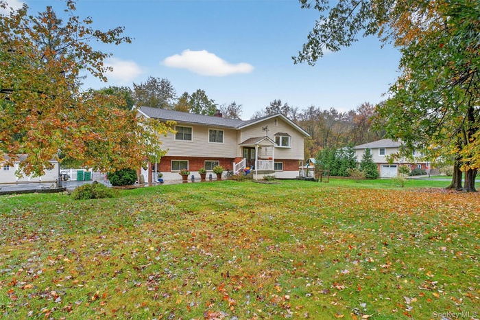 Raised ranch featuring brick siding, a front yard, and a chimney