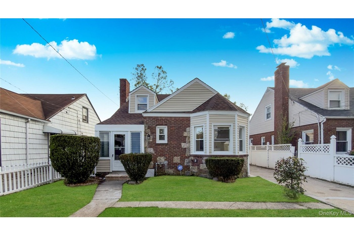 View of front of house featuring a chimney and brick siding