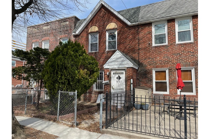 View of front facade featuring brick siding, a shingled roof, a gate, and a fenced front yard
