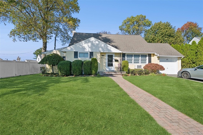 View of front facade featuring a shingled roof and a garage