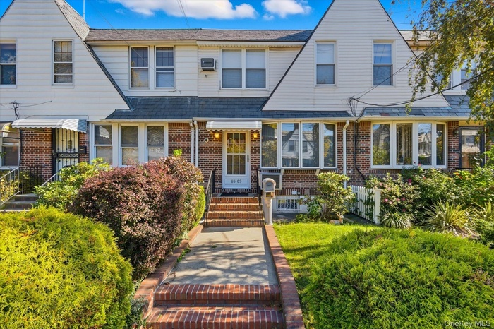 View of front of home featuring brick siding and roof with shingles
