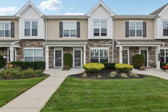 View of front facade with a front yard and stone siding