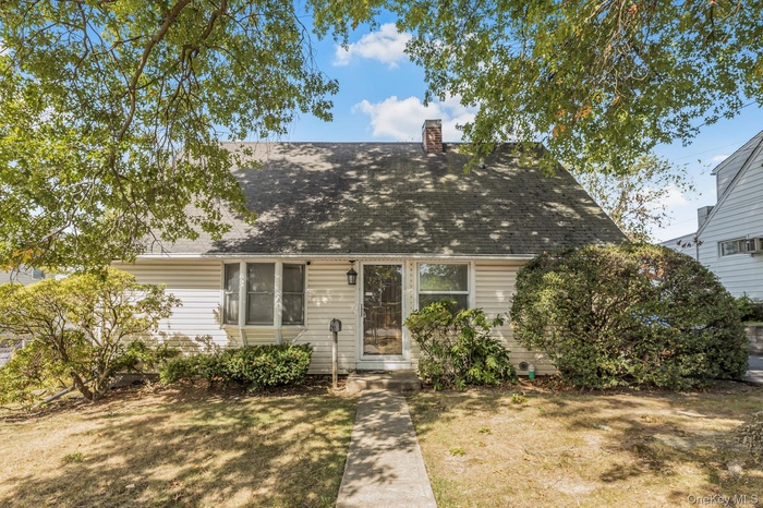 New england style home with roof with shingles and a chimney