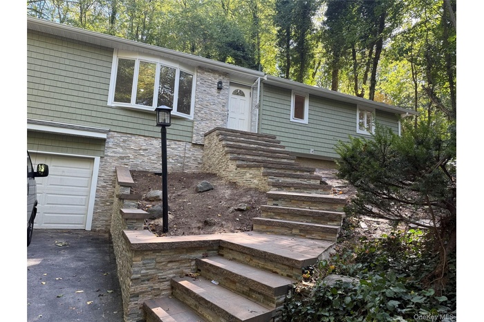 View of front of property featuring stone siding and a garage