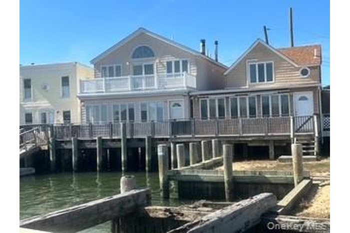 Rear view of property with a sunroom and a water view