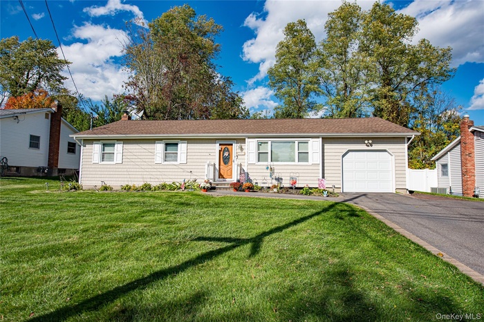 Ranch-style home featuring a front yard, a garage, asphalt driveway, a chimney, and a shingled roof