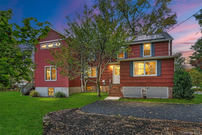 View of front facade featuring a front yard and stairs