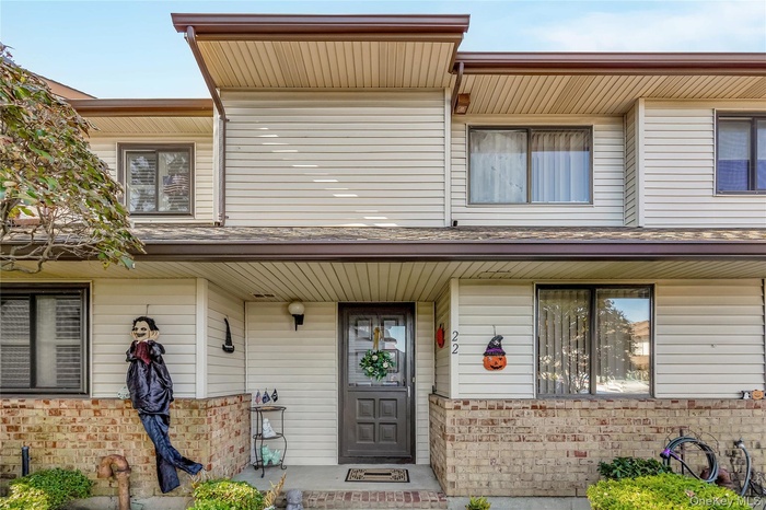 View of exterior entry with brick siding and a porch
