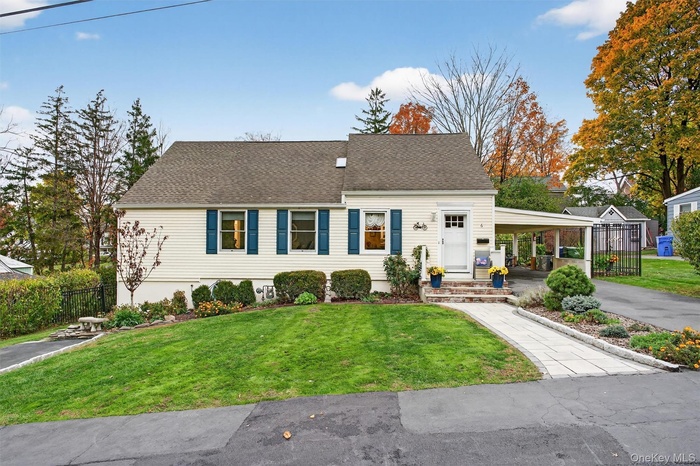 Cape cod home with roof with shingles, an attached carport, and driveway