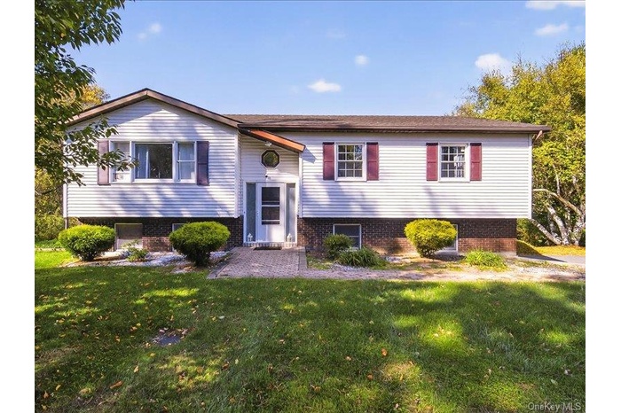 Split foyer home with a front lawn and brick siding