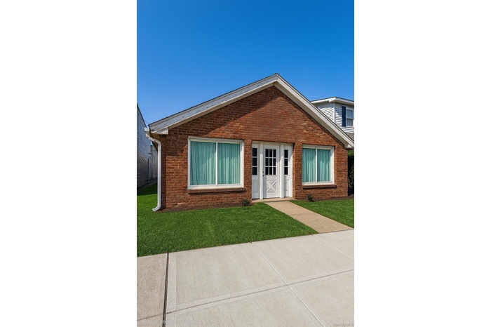 View of exterior entry with brick siding and a yard