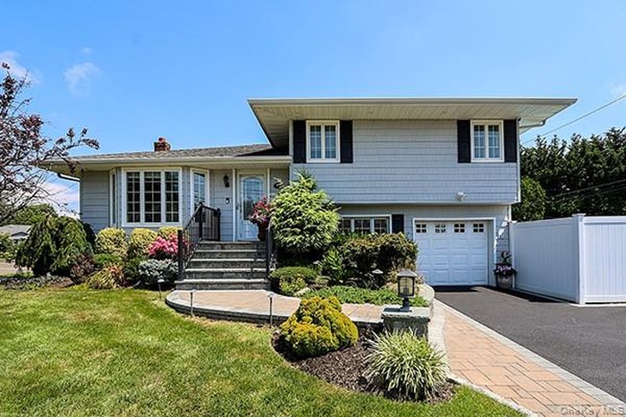 Split level home with a garage, asphalt driveway, and a chimney