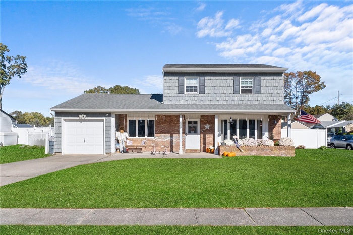 Traditional home with driveway, covered porch, a garage, roof with shingles, and brick siding