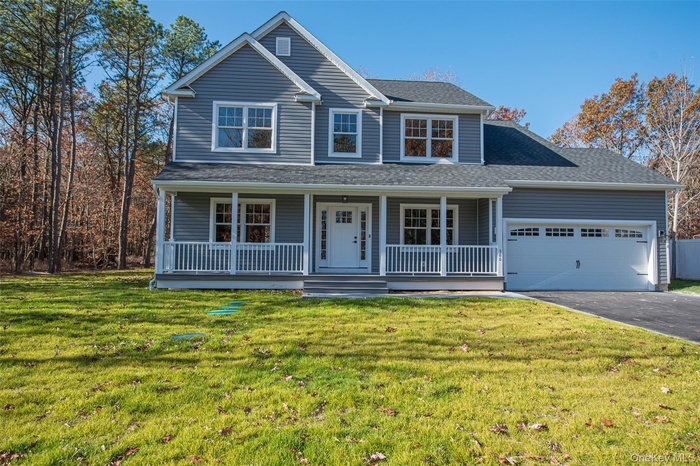 Traditional home with a porch, a front lawn, driveway, and a shingled roof