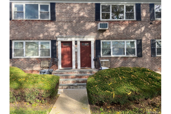 View of exterior entry featuring brick siding and a wall mounted air conditioner