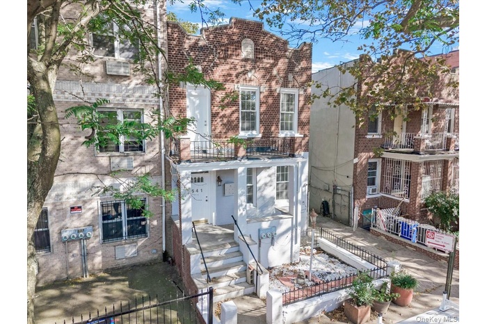 View of front of home with brick siding, a fenced front yard, and a balcony