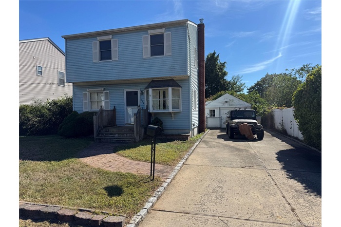 Colonial-style house featuring an outbuilding, a chimney, and a detached garage