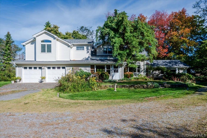 Traditional home with driveway, a front yard, a garage, and roof with shingles